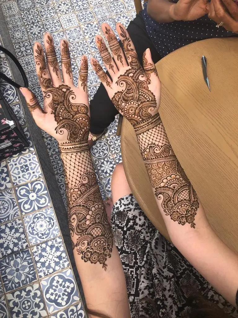 Full-arm bridal mehndi with intricate paisley and lattice covering both forearms and palms