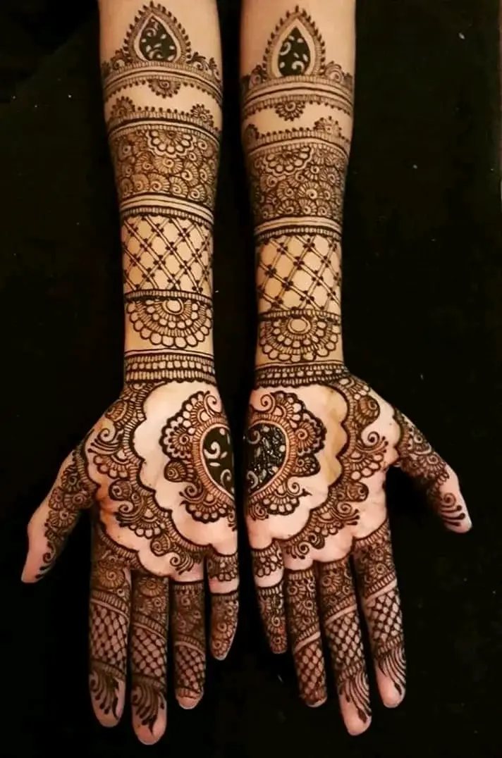 Full-arm bridal mehndi with intricate geometric lattice and floral patterns covering hands and forearms, dark background